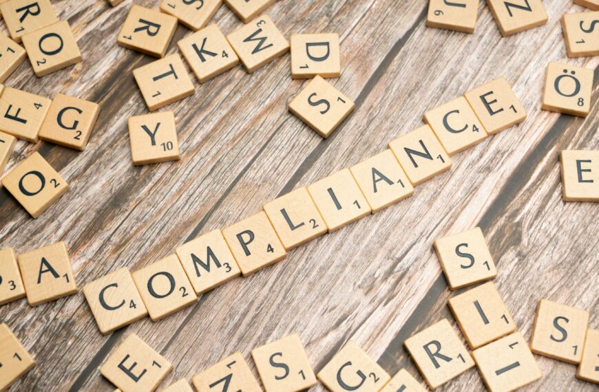 Wooden letter tiles forming the word 'COMPLIANCE' on a rustic wooden background.