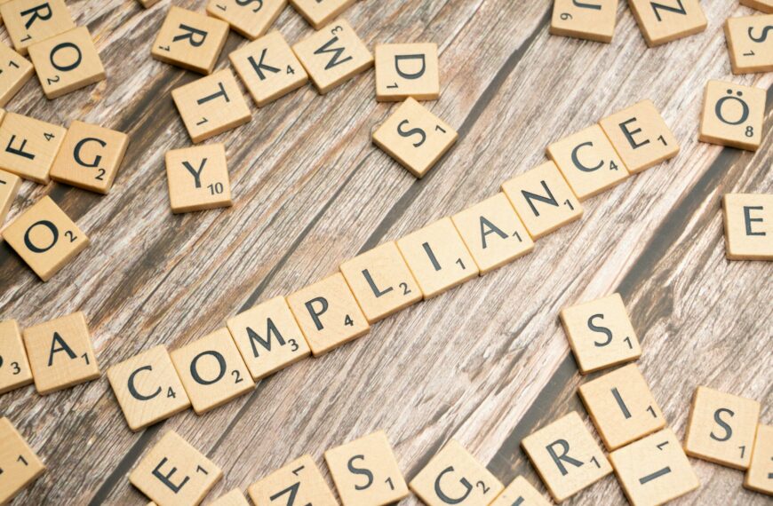 Wooden letter tiles forming the word 'COMPLIANCE' on a rustic wooden background.
